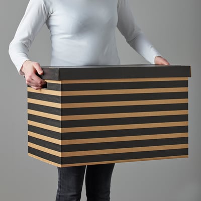 Persoon met grote zwarte en beige gestreepte kartonnen doos met handvatten.