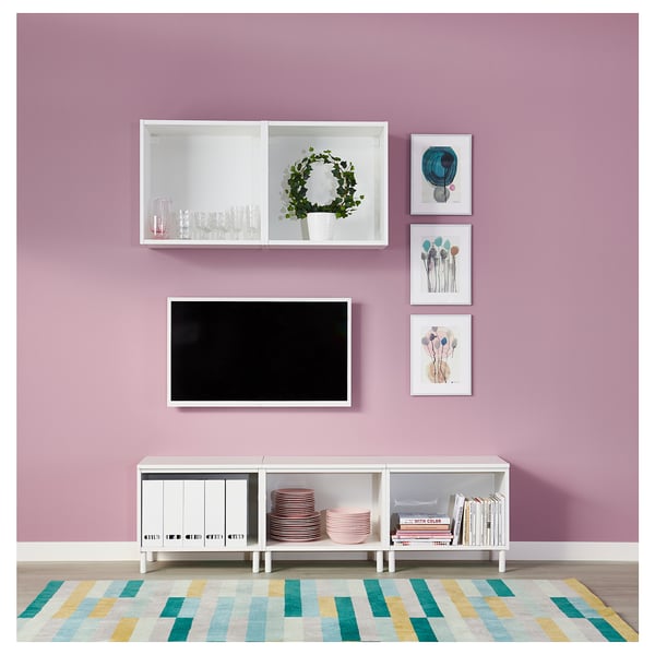 Moderne woonkamer met roze muren, wit PLATSA opbergmeubel, flatscreen tv, kleurrijk vloerkleed en decoratieve kunstwerken.