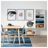 Moderne eetkamer met houten tafel, blauwe decoratie, stadsplattegronden en hanglamp.