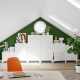 Modern zolderkantoor met groene wanden, witte PLATSA opbergmeubels, oranje stoel, houten vloer en dakramen.