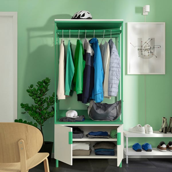 In een groene PLATSA opberger kun je kleding, een helm en een tas kwijt. Het is aan de muur bevestigd met verstelbare poten voor stabiliteit.