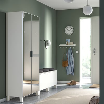 Moderne entree met witte PLATSA kledingkast, bank en klok; groene muur; Hoed & Jas op de plank.