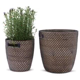 Twee geweven, cilindrische plantenpotten; Een lege, een met groen en paarse bloemen, beide met handvatten.