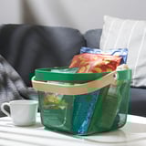 Groene gaasmand met houten handvat houdt snacks op tafel in de buurt van grijze bank.
