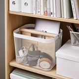 Mesh opbergmand op plank, met laptop en houten voorwerpen, georganiseerd met verdeler, ideaal voor werk of thuis.
