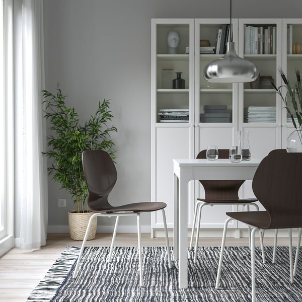 Moderne minimalistische eethoek met witte kast, donkerhouten stoelen en grote plant. Stoel: SIGTRYGG, donker hout, metalen poten.