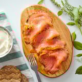 Houten schotel met gesneden sinaasappelgezouten zalm, dillegarnituur, vork, brood en roomsaus.