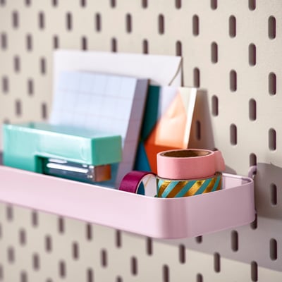 Pegboard-plank met kantoorbenodigdheden, inclusief plakband, pennen en papier.