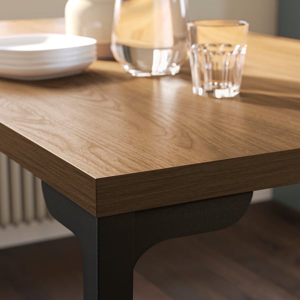 Houten tafel met donkere metalen poten toont schoon, stapelbaar glaswerk en borden en toont duurzaamheid en elegantie.