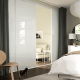 Moderne slaapkamer met grote kledingkast, bed, vaas, raam, kruk en stoel.