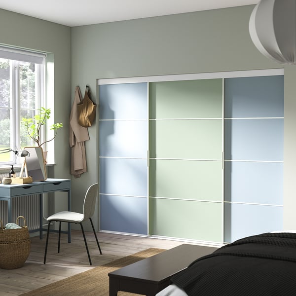 Moderne slaapkamer met grote, veelkleurige schuifkastdeuren en een strak grijs bureau bij het raam.