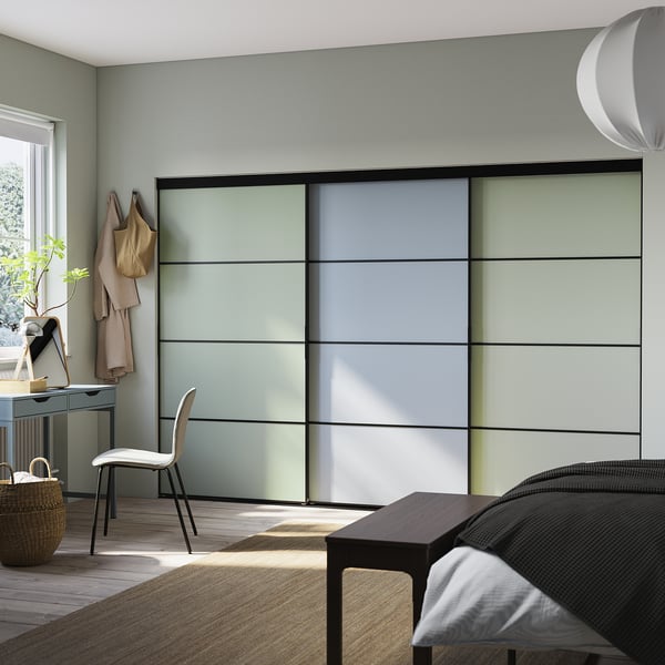 Moderne slaapkamer met lichtgrijze schuifdeuren, witte stoel en hangende jassen.