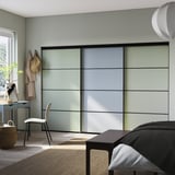 Moderne slaapkamer met lichtgrijze schuifdeuren, witte stoel en hangende jassen.