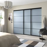 Moderne slaapkamer met blauwgrijze schuifkastdeuren, lichte houten vloer, bed met beige deken, gestreept vloerkleed en hangende lamp.