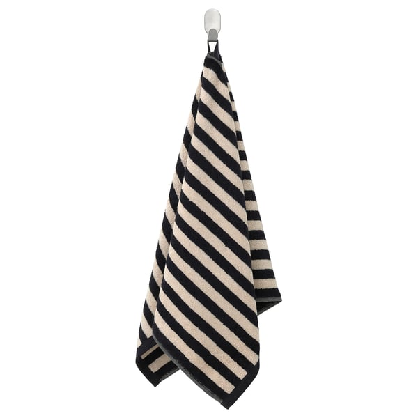 Een hangende zwart-wit gestreepte handdoek, gemaakt van katoen, netjes gevouwen met diagonale strepen.