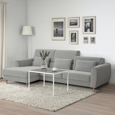 Minimalistische woonkamer met grijze bank, salontafel en galerijwand.