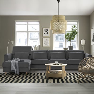 Moderne woonkamer met grote grijze SLATORP sectionele bank, gestreept vloerkleed, salontafel, rieten stoel en hanglamp.