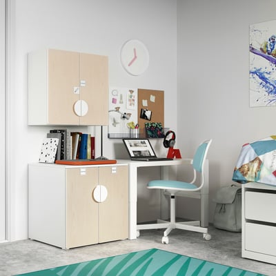 Een kinderkamer met SMÅSTAD witte en lichte houten opbergruimte, een blauwe stoel, een bureau en kleurrijke decoraties.