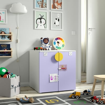 Kinderkamer met veelkleurige klok op paarse kast, speelgoedvoertuigen en wandframes.