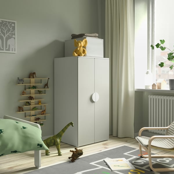 Kinderkamer met groene SMÅSTAD kast, olifant, speelgoedplank, dinosaurusspeelgoed en kleurrijk tapijt. Natuurlijk licht uit het raam.