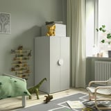 Kinderkamer met groene SMÅSTAD kast, olifant, speelgoedplank, dinosaurusspeelgoed en kleurrijk tapijt. Natuurlijk licht uit het raam.