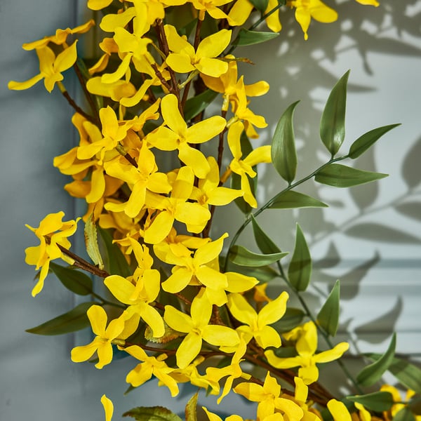 Heldergele kunstbloemen met groene bladeren aan takken, levendig en gedetailleerd.