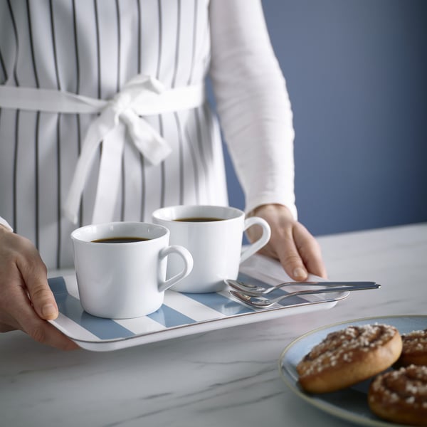 Een persoon die koffie serveert op een stijlvol dienblad, geschikt voor snacks en wanddecoratie.