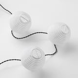Drie onderling verbonden bolvormige witte lampen op een zwarte draad, ideaal voor binnen- of buitendecoratie.