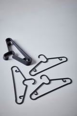 Zwarte plastic hangers; slank, ruimtebesparend ontwerp; plat liggen; drie verschillende vormen; stapelbaar.