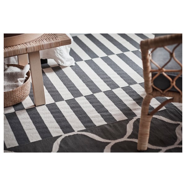 Zwart-wit gestreept tapijt met houten stoel en mand.
