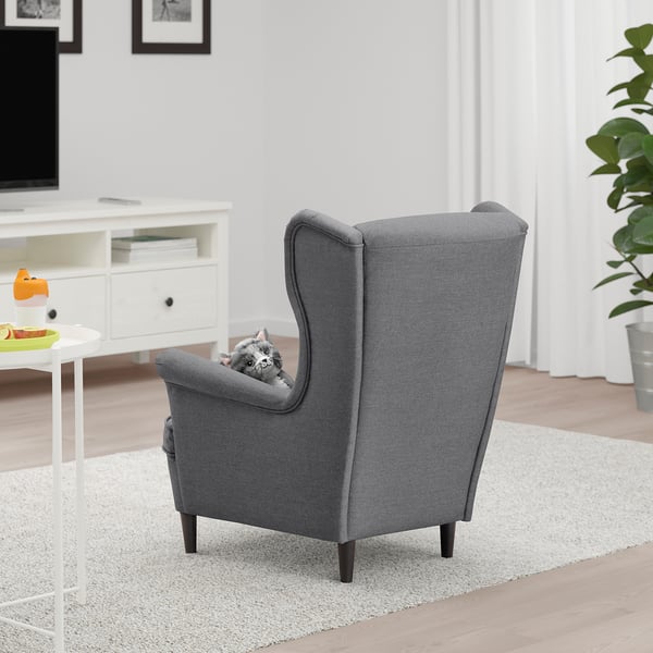 Grijze kinderfauteuil met hoge rugleuning en zijkanten, die comfortabel plaats biedt aan een kat. Onderdeel van een gezellige woonkamer opstelling.