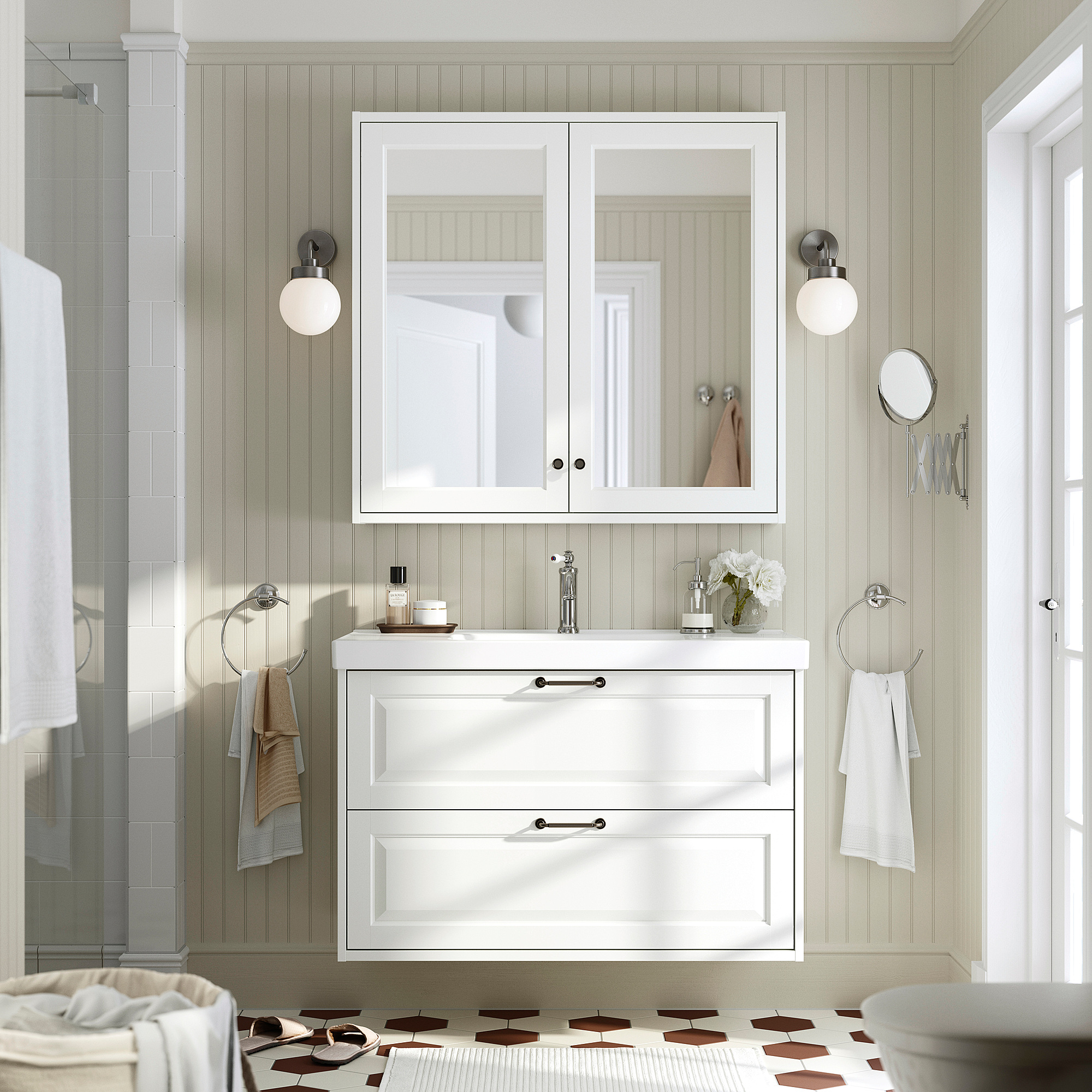Moderne witte badkamer met TÄNNFORSEN badmeubel, lades, keramische wastafel, tegelvloer, wandmontage, ronde verlichting, spiegelkast, handdoeken.