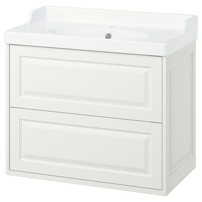 De TÄNNFORSEN is een witte, klassieke, aan de muur gemonteerde badkamerkast met een keramische wastafel. Het heeft afgeschuinde details en een tijdloos ontwerp.