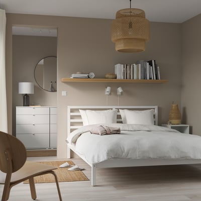 Minimalistische slaapkamer met TARVA bed, planken, spiegel, vloerkleed en hanglamp.