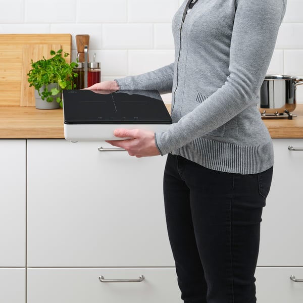 Persoon die een draagbare inductiekookplaat in de keuken gebruikt.