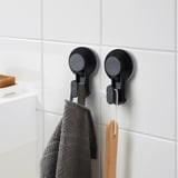 Twee TISKEN haken aan de betegelde muur houden handdoek en spatel vast.