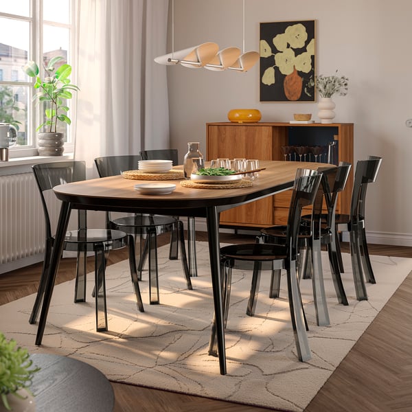 Moderne eetkamer met TJÄRKIL-tafel, zes zwarte stoelen, houten dressoir, grote bloemstukken en hangende lamp.