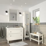 Moderne badkamer met witte TOFTBYN spiegel, kast en bank. Grijze tegels, aan de muur gemonteerde gootsteen en handdoeken.