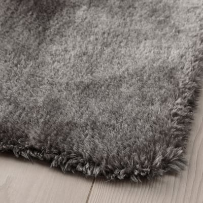 Close-up van zacht, pluche grijs tapijt met getextureerde, ruige oppervlakte op hardhouten vloer.