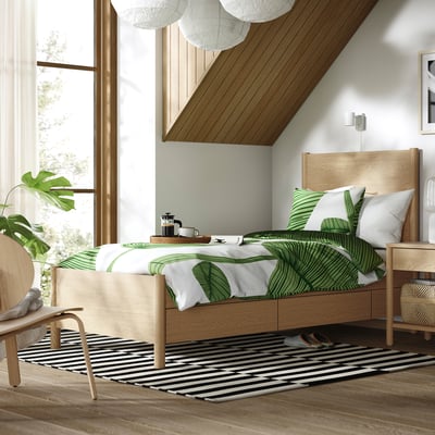 Moderne slaapkamer met eiken bed, groen beddengoed, raam, gestreept tapijt.