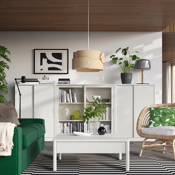 Stijlvolle moderne woonkamer met groene bank, witte TONSTAD kasten, gestreept vloerkleed en houten hanglamp.