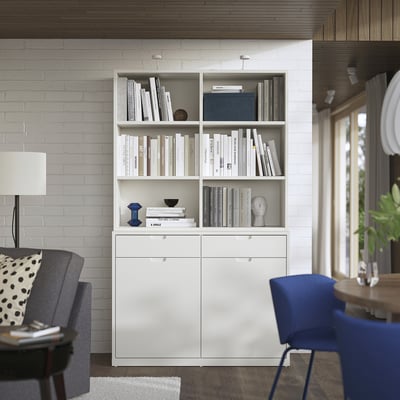 Moderne witte TONSTAD boekenkast en dressoir in woonkamer met grijze stoel, lamp en blauwe stoel.