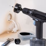 Zwarte IKEA TRIXIG accuboormachine met accessoires, gezien op een wit oppervlak.
