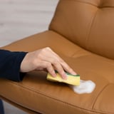 Schoonmakende bank met gele spons, zeepsop, met de nadruk op schuimende werking.