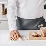 Persoon die het aanrecht schoonmaakt met TRIXIG doek; brood in de buurt.