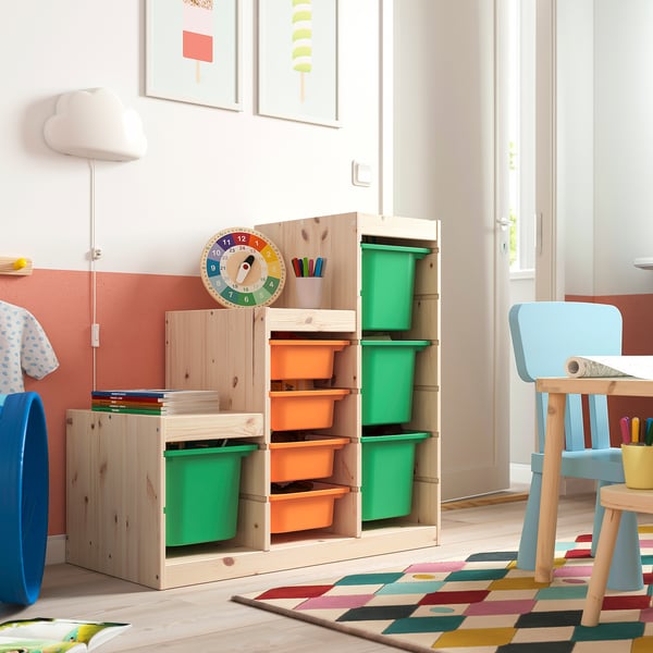 TROFAST opslag: licht houten, groene en oranje dozen, groot, kleurrijk, met verschillende compartimenten. Hoge kast met blauwe stoel, passende speelse kamer.