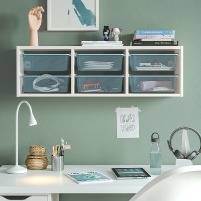 Minimalistische werkruimte met TROFAST plank, blauwe opbergdozen, clean bureau, lamp, tablet en groene muur.
