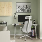 Minimalistische thuiskantooropstelling met wit TROTTEN bureau en stoel, zwarte monitor, houten plank en kunst aan de muur van het stadsgezicht.