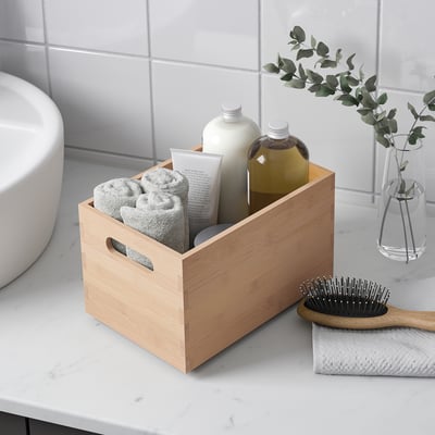 Houten badkamer organizer met handdoeken en toiletartikelen, naast een haarborstel.