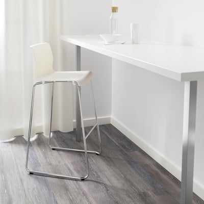 Een minimalistische werkruimte met een witte UTBY-stoel, een wit aanrechtblad en een glazen fles, met de nadruk op een schone en georganiseerde omgeving.